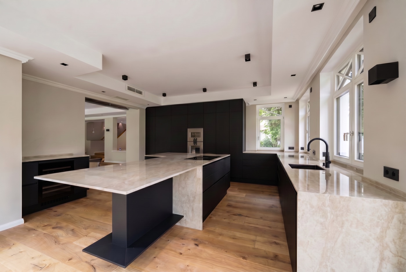 Elegante schwarze Küche mit großer Marmor-Kochinsel in einem Neubau